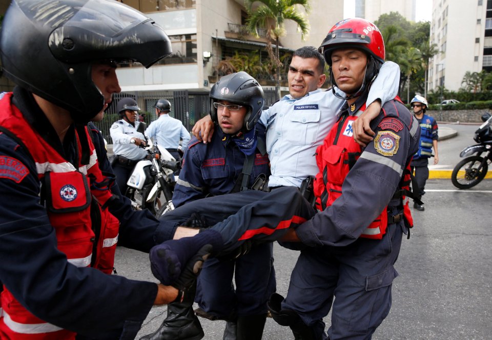 An injured police officer (2nd R) is carried by paramedics during clashes with opposition supporters after a rally to demand a referendum to remove Venezuela's President Nicolas Maduro in Caracas, Venezuela, September 1, 2016. REUTERS/Carlos Garcia Rawlins
